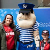 An alumna and her child pose with Louie the Laker at the Detroit Red Wings GVSU Night